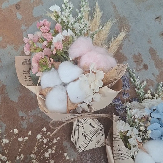 A teeny, ready-to-gift mini bouquet—just perfect for congratulations or a sweet gender reveal moment. Featuring pink or blue cotton snuggled amongst a playful mix of dried florals, each bouquet is wrapped in vintage music sheets for a touch of whimsy. Nestled inside a neutral kraft gift box to keep the colour a secret until the big surprise (Box 15 × 11.2 × 5.6 cm).